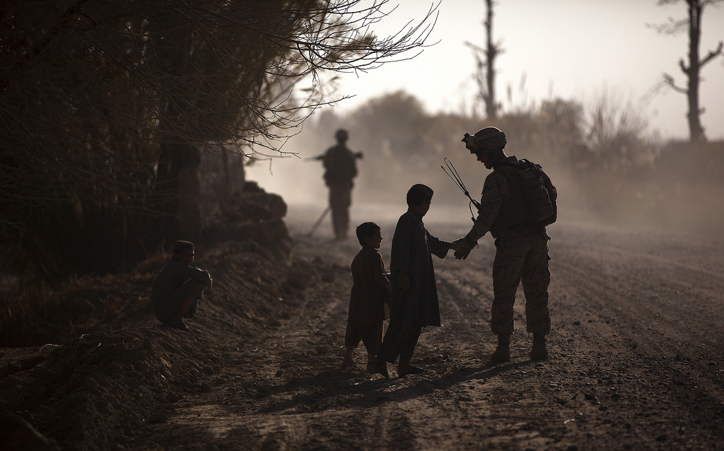 Marine Sergeant Jeremy Holsten, Lima 3/3, greets children while on patrol at Kuchiney Darvishan, Helmand province, Afghanistan, on 18 Dec 2011. Department of Defense photo, used in accordance with Creative Commons license.